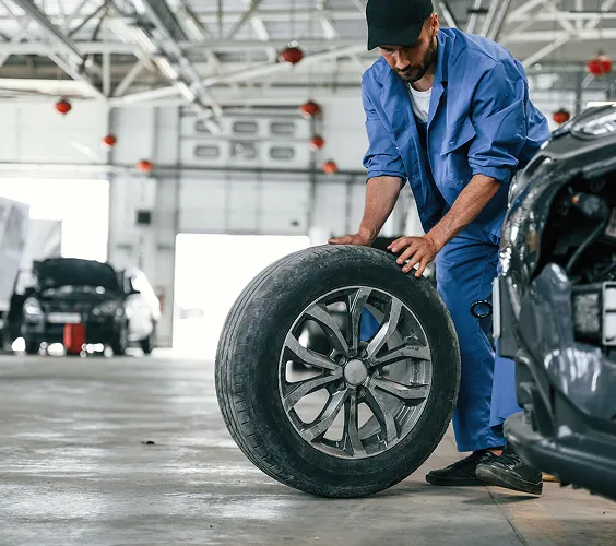 Mécanicien inspectant un pneu de voiture dans un atelier automobile professionnel